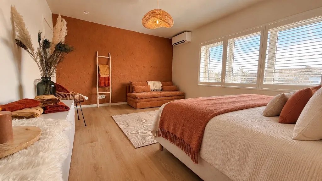 Luxe slaapkamer met terracotta muur, rieten hanglamp en comfortabele bank