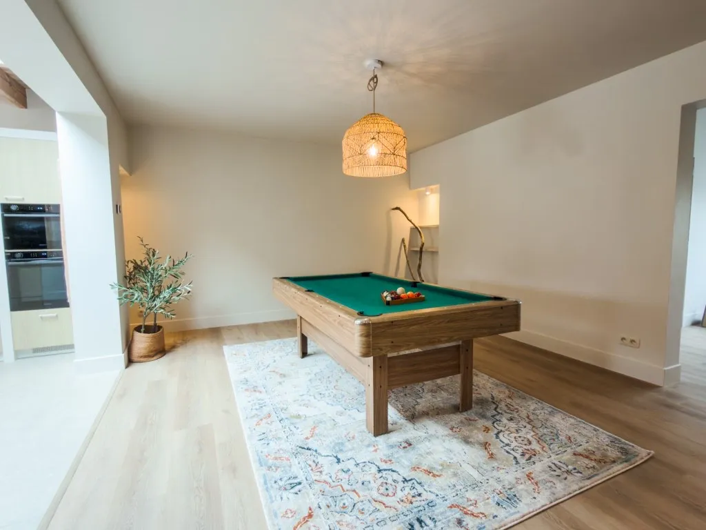 Pooltafel onder een rieten hanglamp in de speelkamer