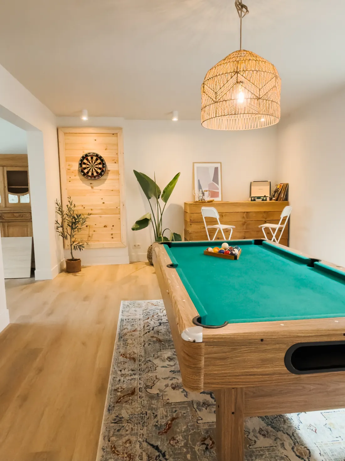 Speelkamer met pooltafel, dartbord en rieten hanglamp