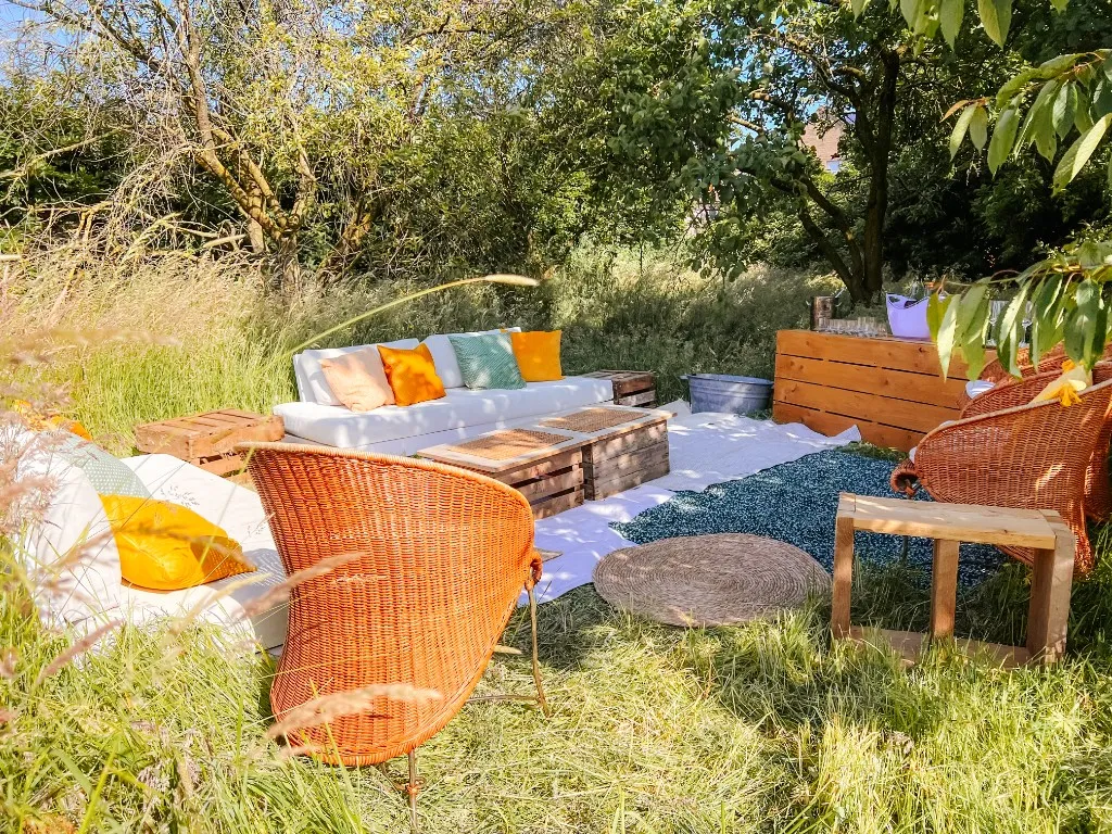 Bohemien tuinlounge met rotanstoelen en witte banken in het hoge gras