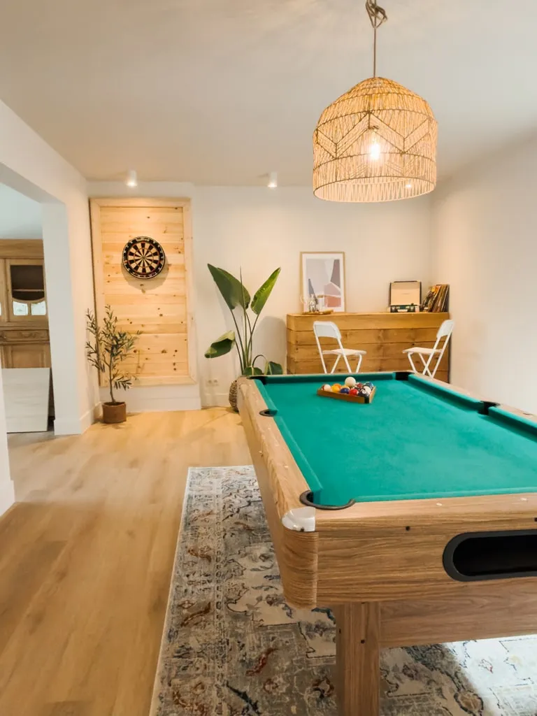 Speelkamer met pooltafel, dartbord en rieten hanglamp