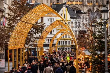 Feestelijk verlichte bogen boven een drukke kerststraat in Antwerpen